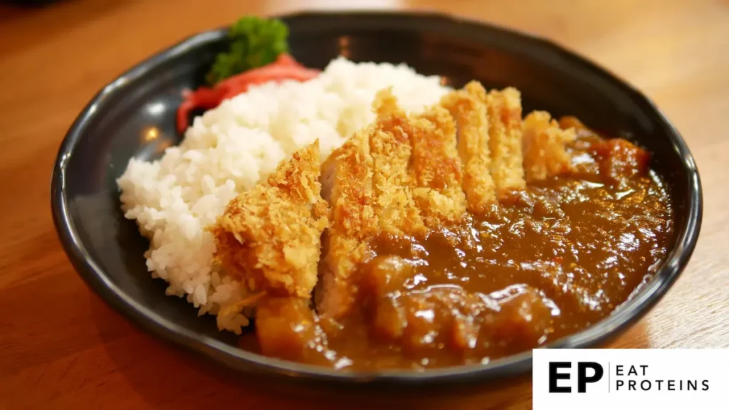 The image shows a plate of "Agu Pork Katsu Curry," a dish consisting of crispy fried pork cutlet (katsu) served over white rice with a rich Japanese-style curry sauce. The pork is sliced and placed beside the curry, with a garnish of pickled ginger and parsley.