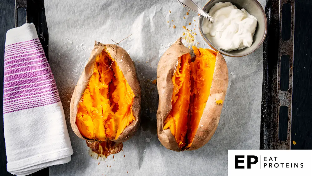 A baked sweet potato drizzled with olive oil surrounded by sour cream