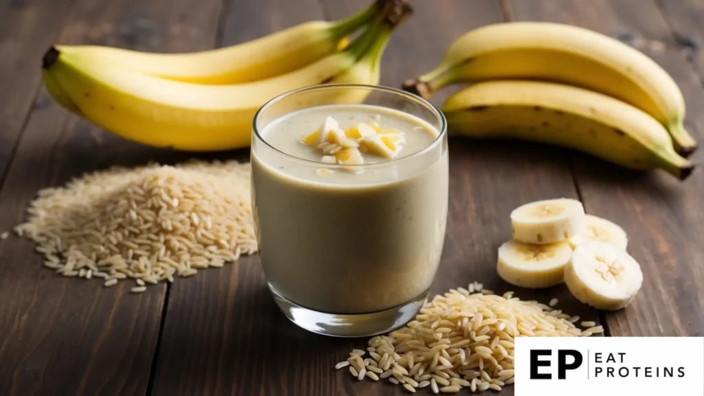 A glass filled with a creamy yellow smoothie, topped with scattered grains of rice and a sliced banana on the rim