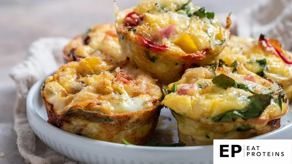 The image shows a plate of freshly baked egg muffins filled with a variety of colorful vegetables and cheese. 