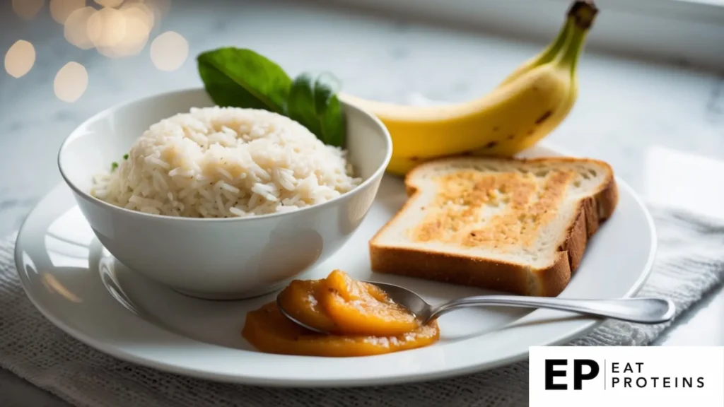 A bowl of steamed rice, a banana, a slice of toast, and a spoonful of applesauce arranged on a white plate