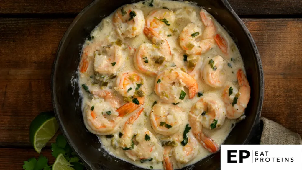 A pan of coconut lime shrimp with colorful low fodmap ingredients on a wooden table, surrounded by fresh herbs and citrus fruits