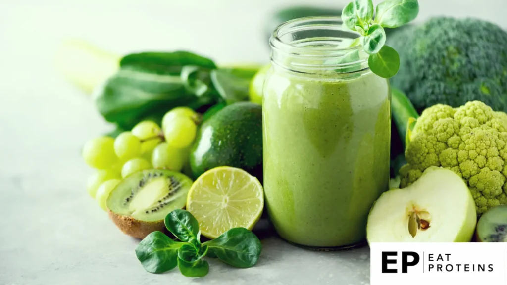 A green smoothies on glass surrounded by fresh fruits and vegetables