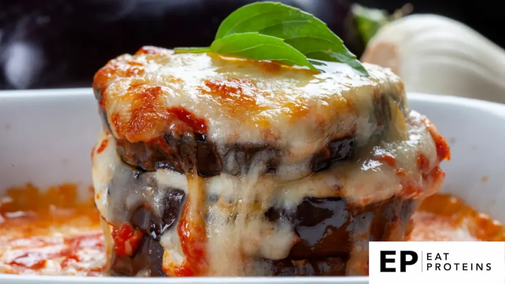 The image appears to be a Mediterranean Eggplant Lasagna, a dish made from layers of eggplant, tomato sauce, and cheese, often topped with fresh herbs. It’s a popular recipe in Mediterranean diets, offering a low-carb and nutritious alternative to traditional pasta lasagna. The melted cheese and sauce give it a hearty and comforting appearance, making it a suitable option for those looking for a high-protein, plant-based meal