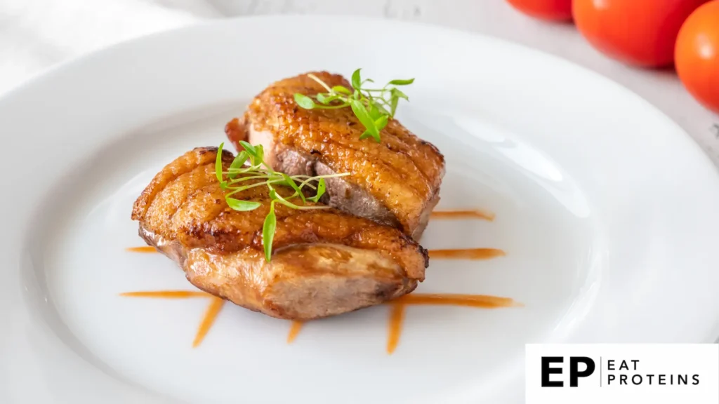 A sizzling duck breast cooking in a white plate, surrounded by herbs and spices