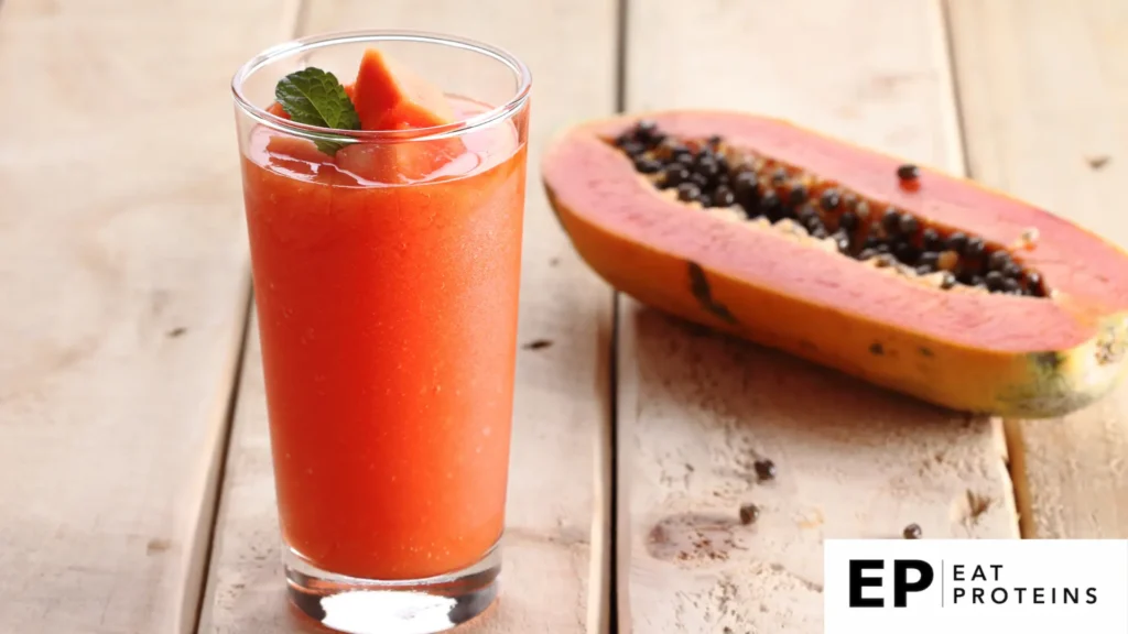 A glass of papaya and almond smoothie, surrounded by fresh papaya