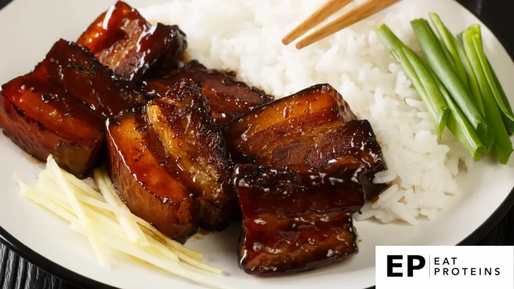 The image shows a plate of "Rafute," a traditional Okinawan dish featuring braised pork belly in a rich, dark glaze. The pork is served alongside steamed white rice, thinly sliced ginger, and green onions.