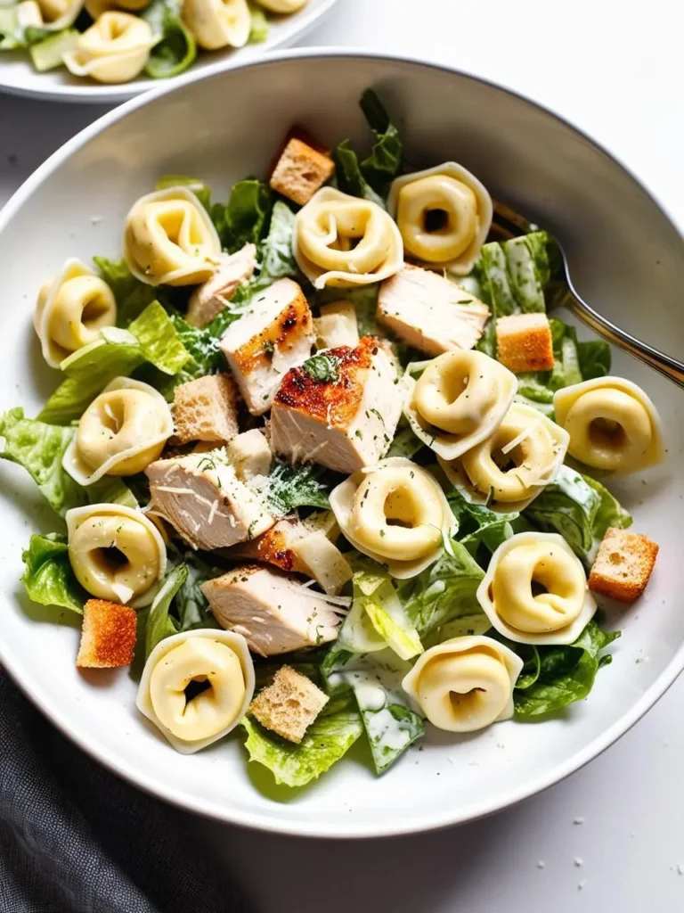 A close-up view of a bowl of Caesar salad with tortellini. The salad is made with romaine lettuce, croutons, grilled chicken, tortellini, and a creamy Caesar dressing.